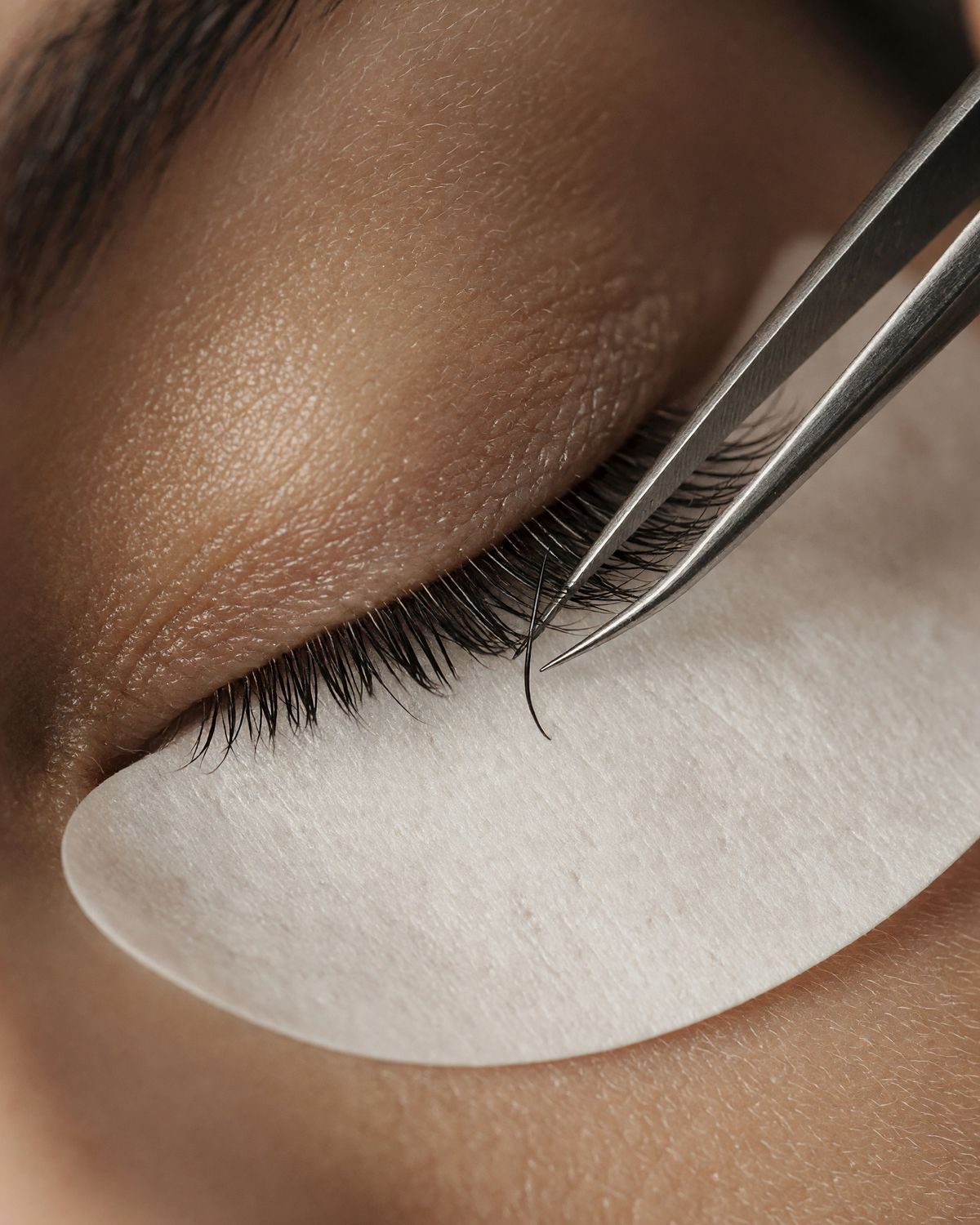 An artist's hands isolating a single lash